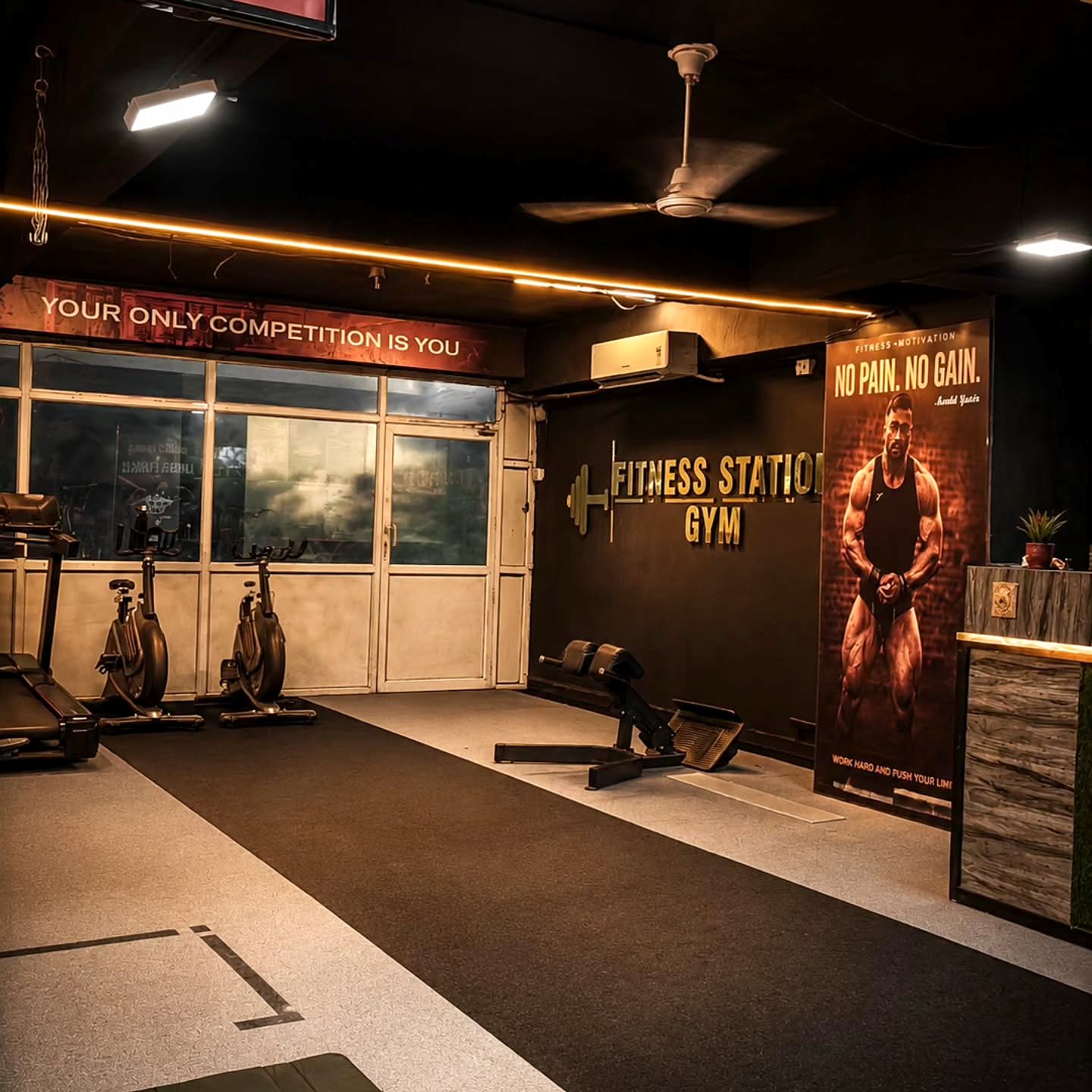 Inside Fitness Station Gym, 48 Chambers, Jhansi — cardio row, reception and the 'Your only competition is you' wall
